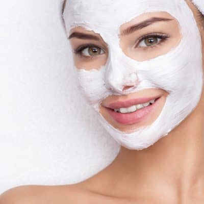 smiling-woman-in-spa-salon-with-cosmetic-mask-on-f-6EGH9B3.jpg